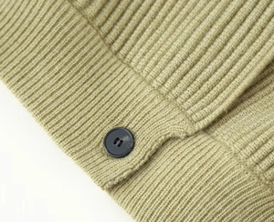 Close-up of olive green ribbed knit fabric with a black button on the edge