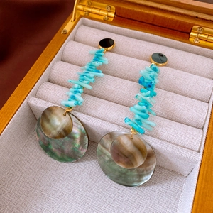 Detail of bamboo-style shell earrings with blue beads in a premium wooden jewelry box