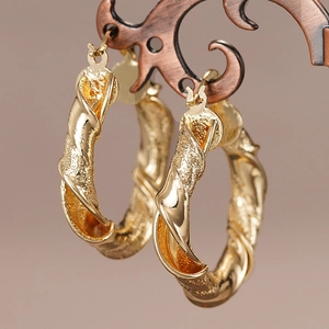 Detail von goldenen Creolen mit einzigartiger gedrehter Spiralstruktur und Politur