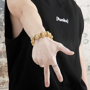 Close-up of gold skull link bracelet and vintage textured rings in punk style