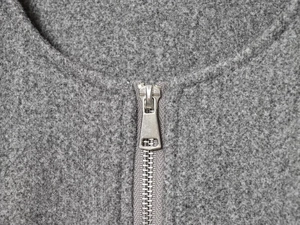 Macro detail of silver metal zipper closure on a grey fleece bomber jacket collar
