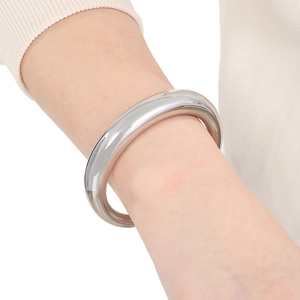 Gros plan d'un large bracelet en acier inoxydable poli argenté porté au poignet
