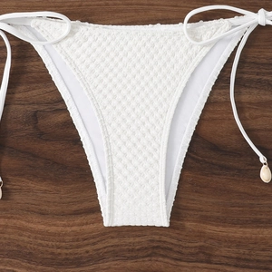 Close-up of white textured bikini bottoms with side ties and decorative shell charms