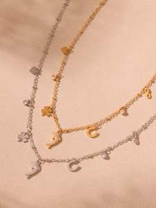 Detail of 18k gold plated necklace featuring dolphin and clover charms with 5A zircon