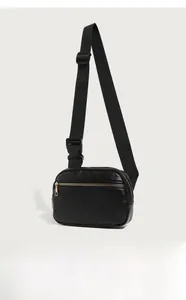 Detail of lychee textured PU leather cross-body bag with golden metal zippers and buckle