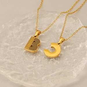 Gros plan de pendentifs en acier titane doré à texture d'écorce avec lettres B et C