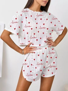 Detail of white hollow knit fabric with red heart prints and side slit on the shorts
