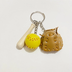 Close-up of mini wooden baseball bat, yellow ball, and brown leather glove keychain
