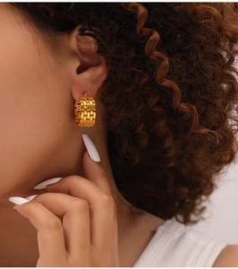 Close-up of gold-plated titanium steel earrings with thick woven chain texture on model