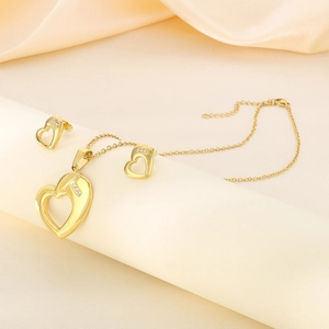 Detailed view of gold heart jewelry set with necklace and earrings on silk