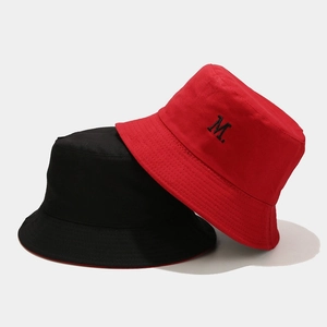 Dettaglio di cappelli a secchiello in cotone rosso e nero con logo M ricamato e cuciture