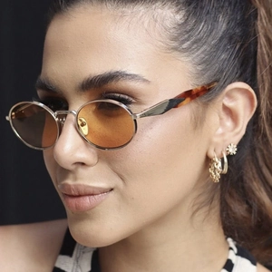 Retro oval metal sunglasses with orange lenses and amber textured temples on a female model