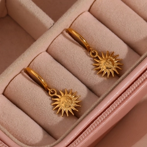 Close-up of golden sun face relief pendant earrings in a pink jewelry box organizer