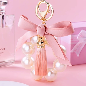 Detail of pink bow keychain with large imitation pearls and elegant fringe tassels