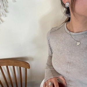 Close-up of model wearing daisy flower pendant necklace, earrings and ring set
