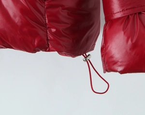 Detail of red glossy puffer jacket featuring hem drawstring and silver metal toggle