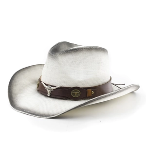 Détail d'un chapeau de paille de cowboy avec ruban en cuir et emblème de tête de taureau