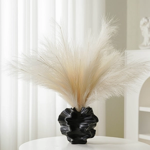 Modern white ceramic vase with wavy texture and fluffy reed grass for home decor