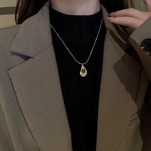 Detail of vintage gold snake chain necklace with tiger eye stone pendant on a model