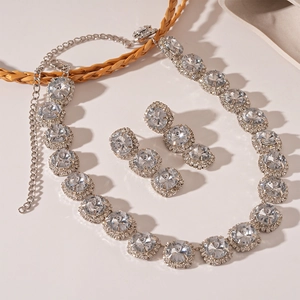 Macro detail of luxury crystal jewelry set featuring silver necklace and round stud earrings