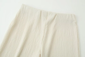 Macro shot of cream white high-waist trousers with elegant pleated fabric texture
