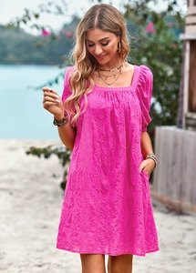 Dettaglio dell'abito fucsia con scollo a quadrato, ricamo traforato e maniche a sbuffo