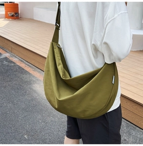 Outdoor shot of green crescent oxford crossbody bag with adjustable wide shoulder strap