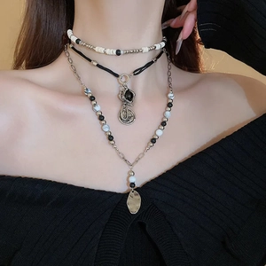Detail view of tiered bohemian necklace with wood beads and metallic charms on a model