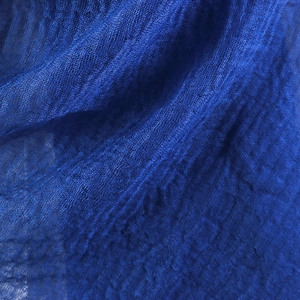 Macro shot of navy blue wrinkled cotton scarf fabric showing gauzy woven texture and frayed edges