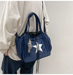 Detail of dark blue waterproof nylon tote with white star and checkerboard bear charm