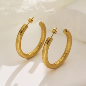Macro detail of high-shine gold hollow hoop earrings with minimalist polished surface