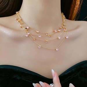 Vue détaillée d'un collier multicouche doré avec des pierres de zircon rose sur un modèle