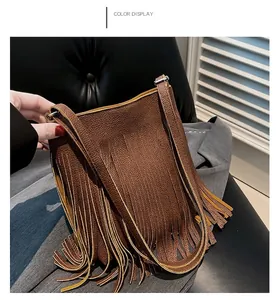 Detailed close-up of brown textured leather bag with bohemian long fringe and metal buckle