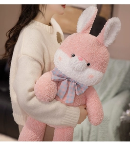 Close-up of soft pink and white plush bunny toy with a blue checkered ribbon bow tie