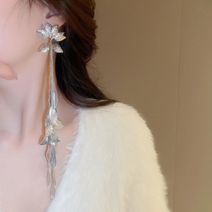 Gros plan sur des boucles d'oreilles à pompon argenté avec fleurs et feuilles