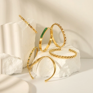 Stack of 18K gold plated stainless steel bangles with zircons on white stone pedestals