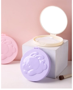 Close-up of portable purple bunny folding mirror and beige comb set on pink background