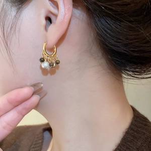 Detail of 18k gold plated hoop earring with tiger eye bead and hanging white pearl