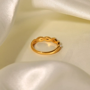 Macro detail of golden twisted titanium steel ring with small pearls on beige silk fabric