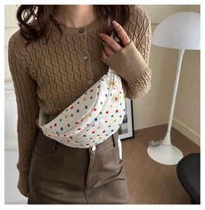 Dettaglio di una borsa a sella bianca con pois colorati indossata come borsa a tracolla