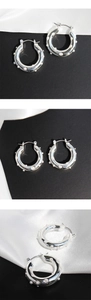 Close-up of silver hoop earrings featuring polished finish and small white pearl inlay