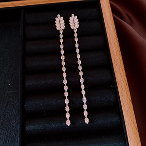 Détail de boucles d'oreilles feuilles dorées 18K avec zircons brillants sur velours