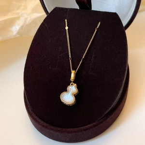 Gros plan d'un pendentif Wulu doré avec nacre blanche sur un présentoir en velours chic