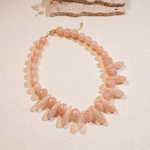 Detail of pink acrylic round and teardrop beads on a minimalist necklace with gold clasp