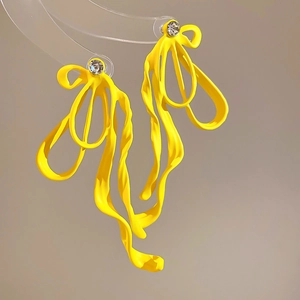 Macro shot of yellow matte bow earrings with crystal accents on a display stand