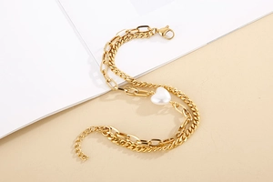 Detailed macro of gold double-layer chain bracelet featuring a heart pearl pendant