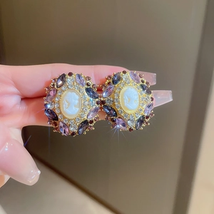 Macro shot of vintage cameo earrings with purple crystals and gold engraving details