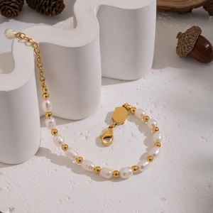 Detail of freshwater pearl bracelet with golden beads and lobster clasp on white decor