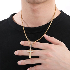 Detail shot of a double-layered gold and silver cross pendant on a gold box chain