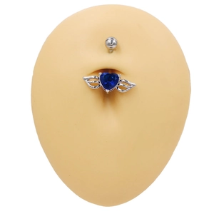 Gros plan d'un piercing de nombril en zircon bleu en forme de cœur avec ailes